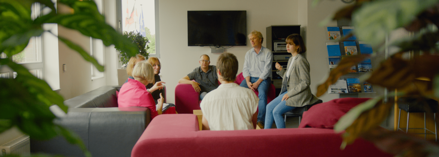 Personen verschiedenen Alters sitzen in einem Kreis und reden