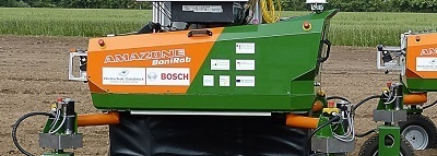 Der grün orangene Agrarroboter auf einem Feld