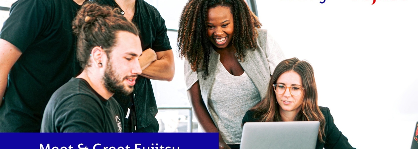 Fünf Personen schauen auf einen Laptop und lachen.