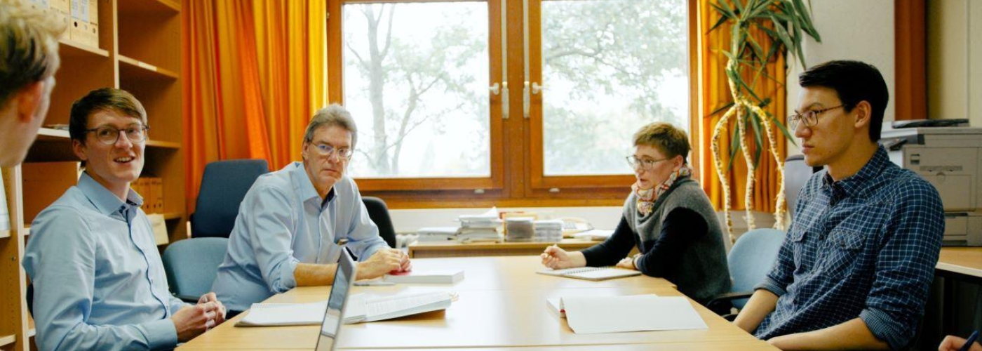 Personen sitzen an einem Tisch und sprechen miteinander