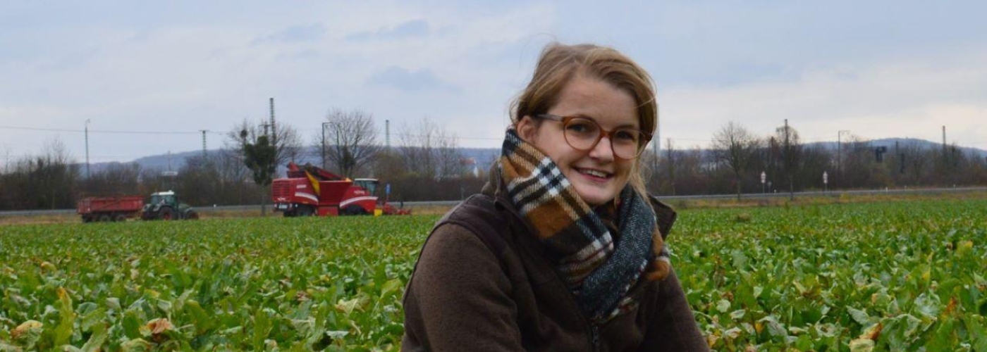 Frau sitzt in grünem Ackerfeld
