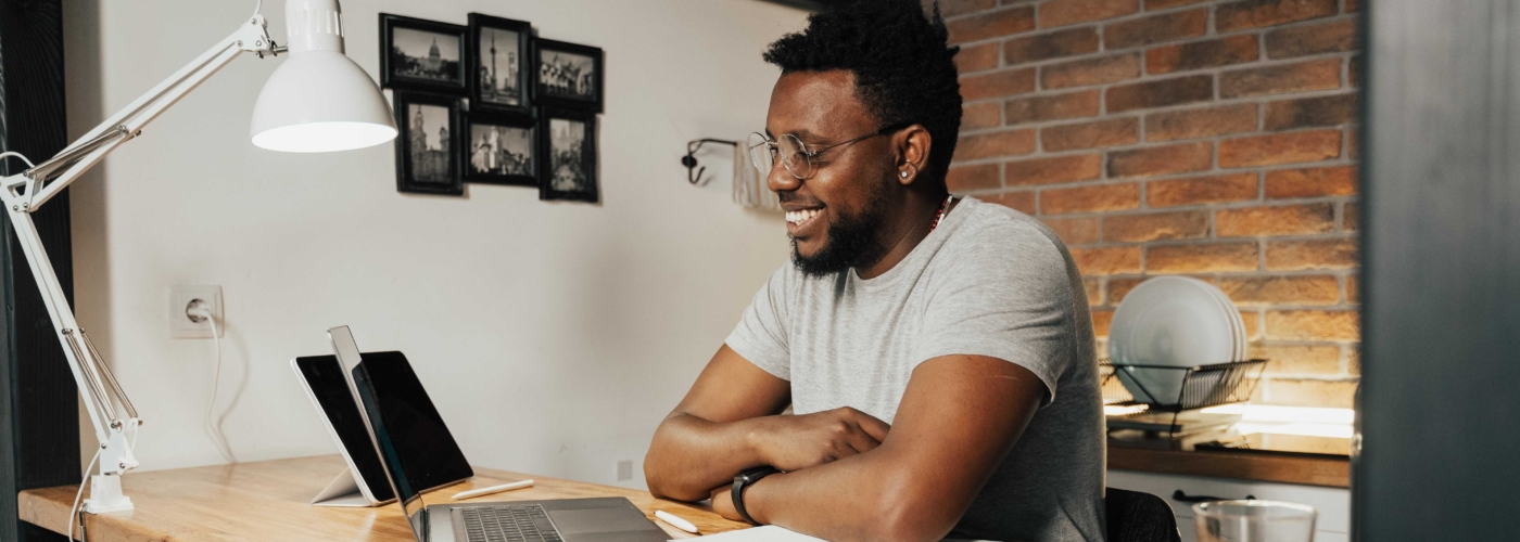 Ein Mann sitzt am Tisch vor einem Laptop
