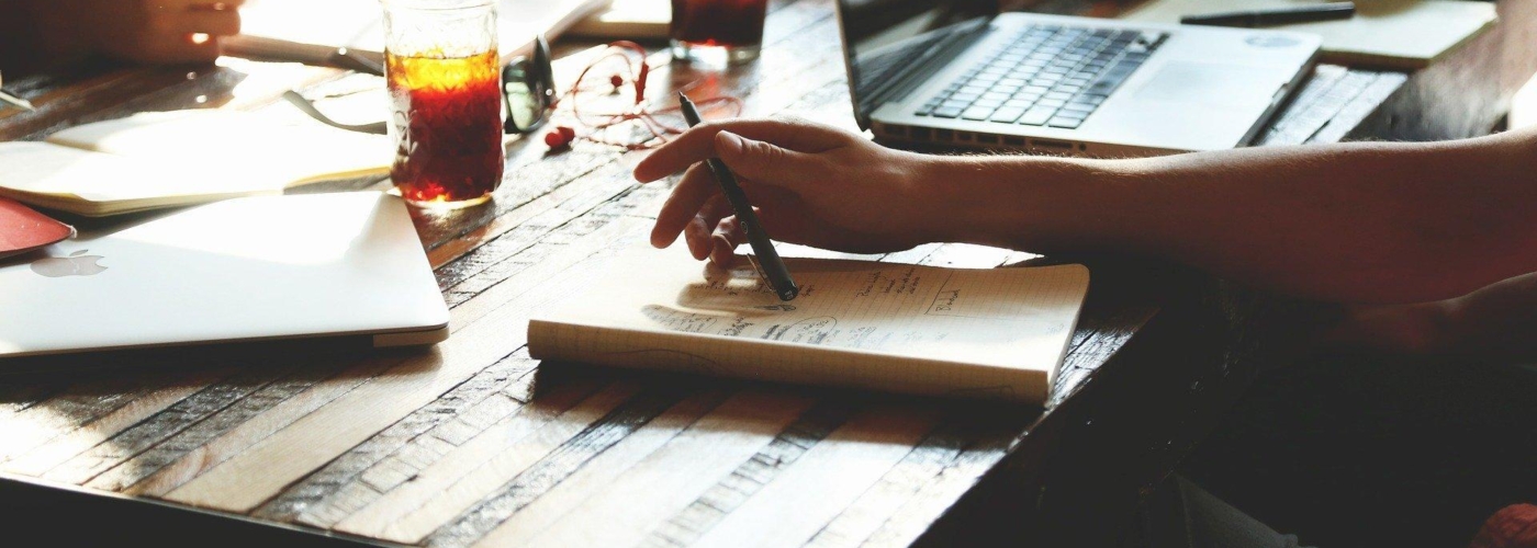 Mehrere Personen sitzen am Tisch und arbeiten mit Papier und Laptops