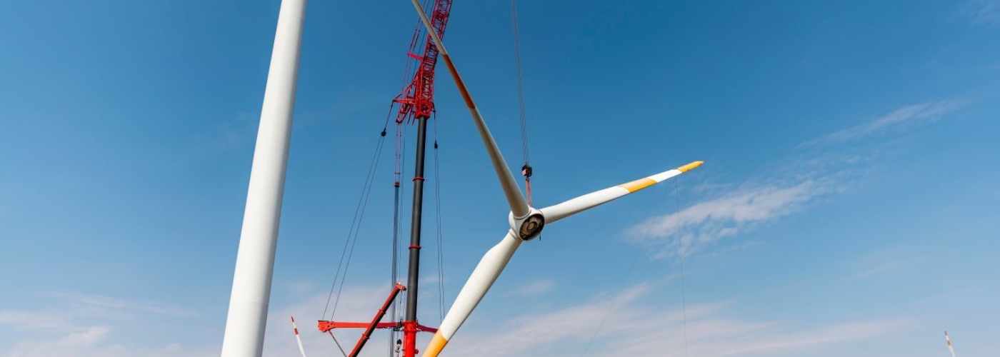 Windkraftwerk während der Bauphase mit Kran im Hintergrund