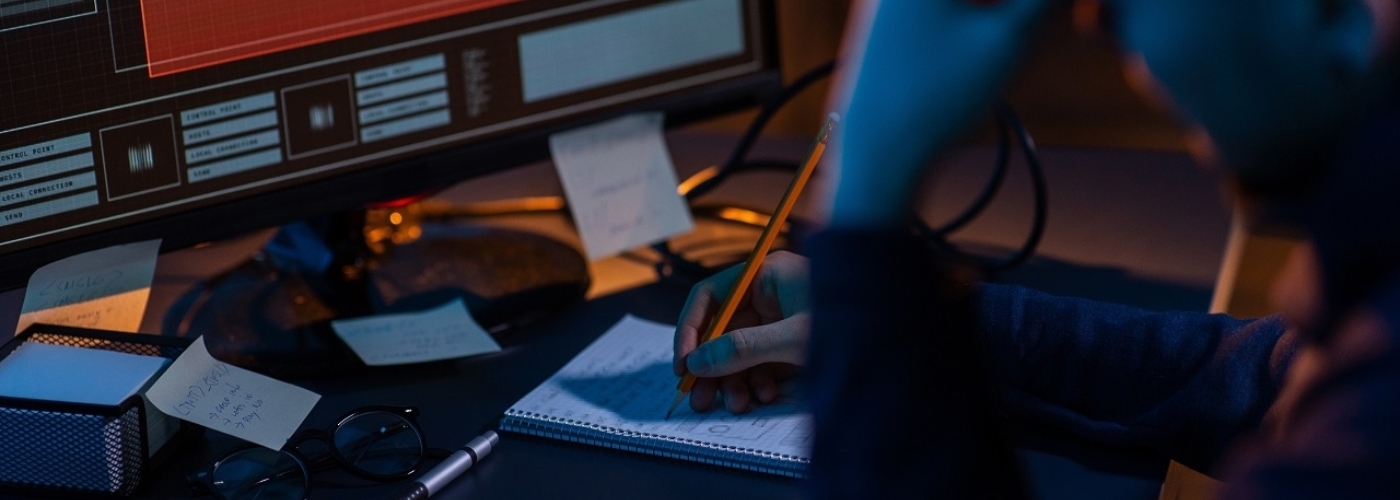 Person arbeitet an einem Schreibtisch mit Stift und Papier
