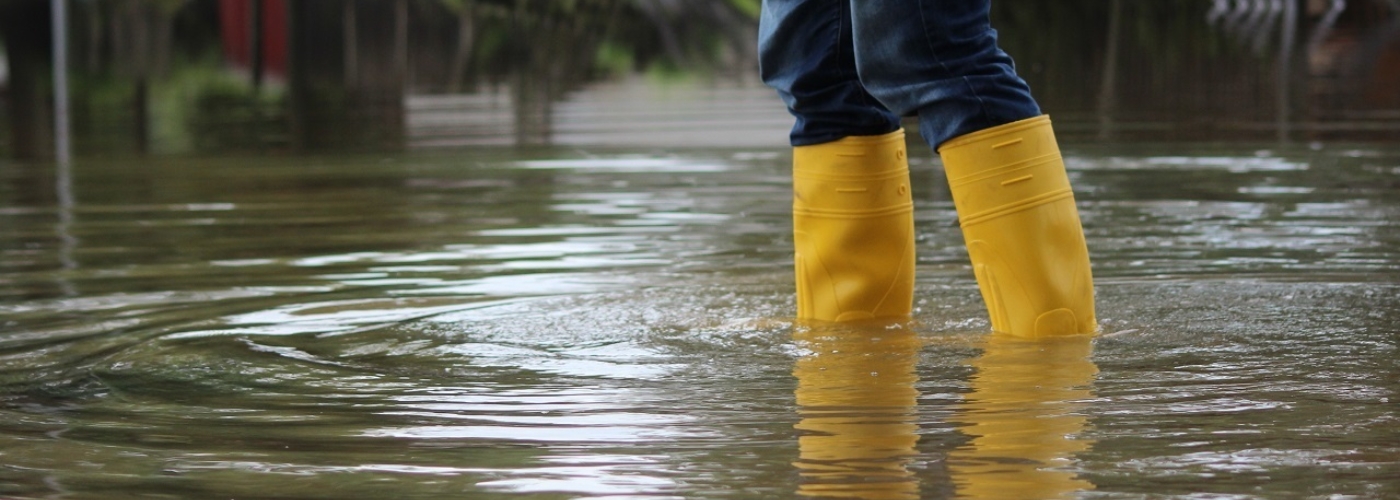 Person in gelben Gummistiefeln steht in Wasser, das bis zur Wade ragt.