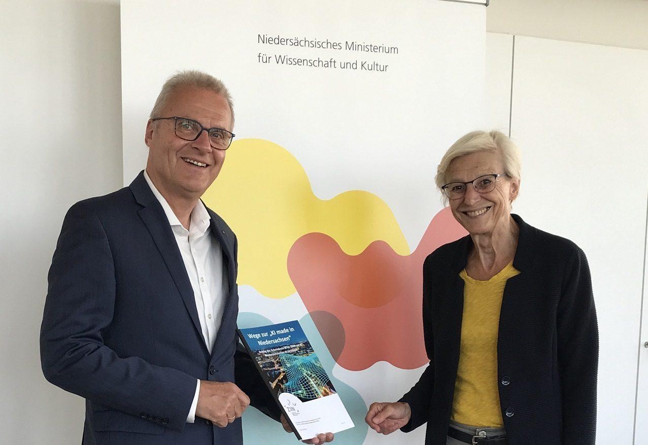 Ein Mann übergibt einer Frau ein Heft.